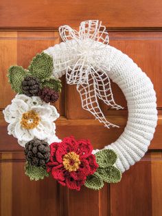 a crocheted wreath with flowers on the front door