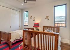 a bedroom with two beds and a red striped rug on the floor in front of windows