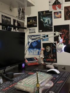 a computer monitor sitting on top of a desk next to a keyboard and mouse in front of a wall covered with posters