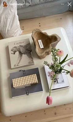 a coffee table topped with books and vases on top of it next to a couch