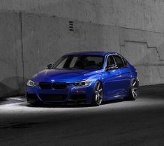 a blue car is parked in an empty parking garage with concrete walls and flooring