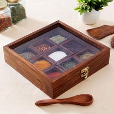 a wooden box filled with spices on top of a table next to spoons and other items