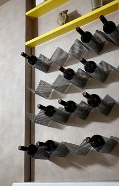 a wine rack with several bottles on it in a room that has white walls and yellow shelves