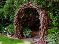 an arch made out of branches in the middle of a garden