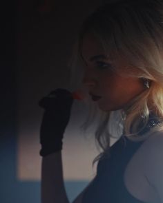 a blonde woman is brushing her teeth in the dark