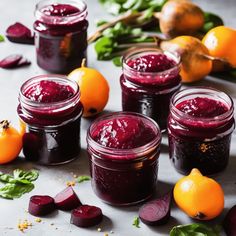 jars filled with beets and oranges on top of a table next to vegetables