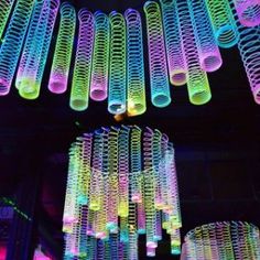 colorful lights hanging from the ceiling in a dark room with many tubes attached to it