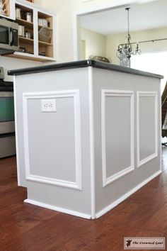 a kitchen island with an oven and microwave in the back ground, next to a hardwood floor