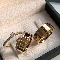 two gold rings sitting in a box on top of a table