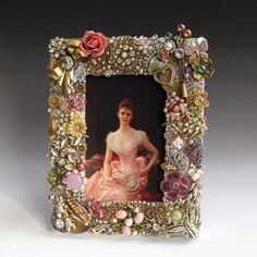 an ornate photo frame with a woman in a pink dress surrounded by flowers and pearls