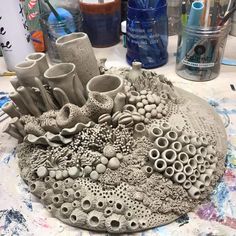 a sculpture made out of clay sitting on top of a table next to other art supplies