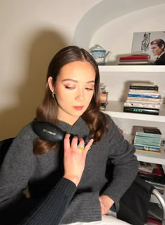 a woman sitting on a bed holding a hair dryer in her hand and looking down