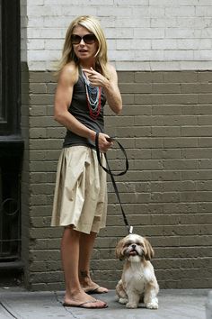 a woman is standing on the sidewalk with her dog