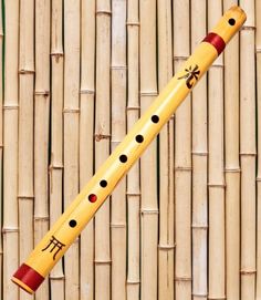 a bamboo wall with a musical instrument hanging from it's side and the top part of its flute sticking out