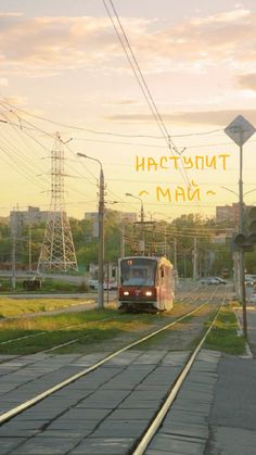 the train is traveling down the tracks near some power lines and traffic lights in an urban area