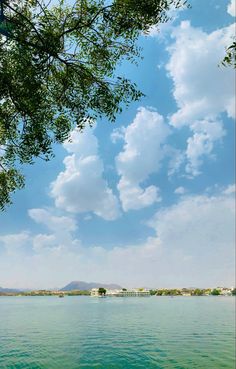 the water is green and blue with clouds in the sky