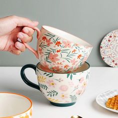 a person is holding a spoon in front of three cups with food on the table