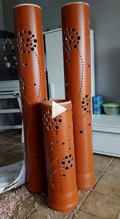 three tall orange vases sitting on top of a tile floor next to a mirror