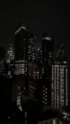 the city skyline is lit up at night, with skyscrapers in the foreground