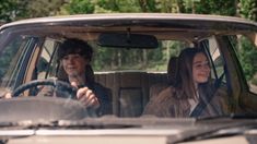 a man and woman sitting in the back seat of a car, smiling at each other