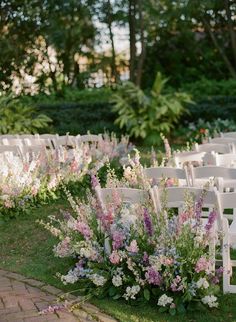 an outdoor ceremony with white chairs and flowers