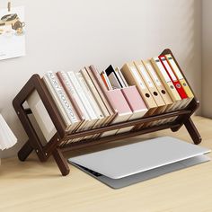 a laptop computer sitting on top of a wooden desk next to a bookshelf