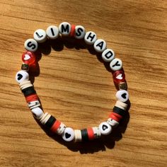 a close up of a beaded bracelet on a wooden surface with words written in small letters