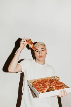 a man holding a pizza in front of his face