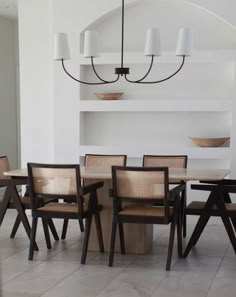 a dining table with six chairs and a chandelier hanging from the ceiling above it