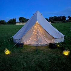 a white tent with fairy lights in the grass