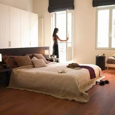 a woman is standing in the doorway of a bedroom that has hardwood floors and white walls