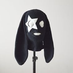 a black dog with a white star on it's face is wearing a knitted mask