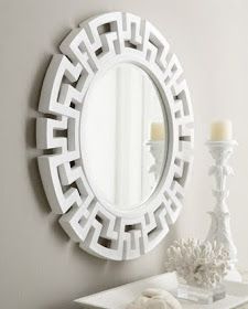 a white mirror sitting on top of a table next to a vase and two candles