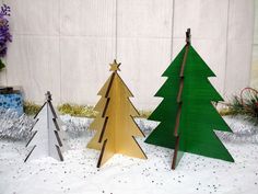 three wooden christmas trees sitting next to each other on a white cloth covered tablecloth