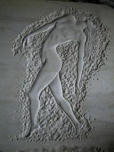 a stone carving depicting a man standing in the sand with his hands on his hips