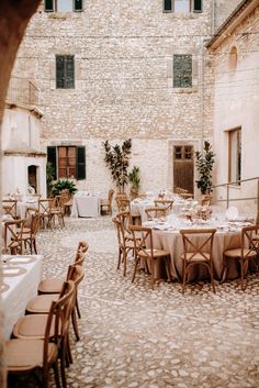 an outdoor dining area with tables and chairs set up in front of a brick building