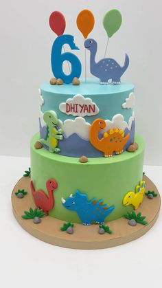 a birthday cake decorated with dinosaurs and balloons