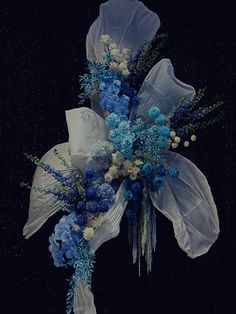 a bouquet of blue and white flowers on a black background