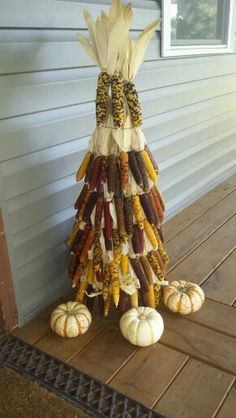 an arrangement of corn on the cob and pumpkins is sitting on a porch