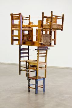 an art piece made out of wood and rope with multiple chairs on top of it