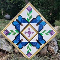 a patchwork quilt sitting on top of a pile of grass next to a tree