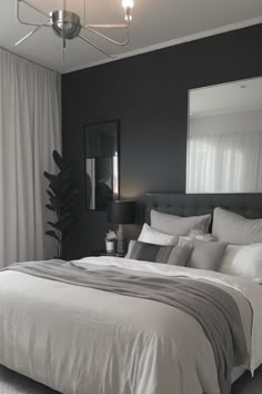 a bedroom with black walls and white bedding in front of a large mirror on the wall