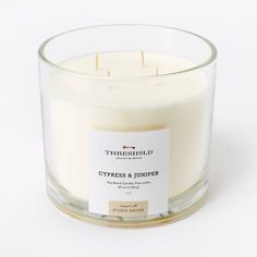 a white candle with a label on it sitting in front of a white background that says cypress and lavender