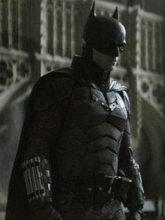 the dark knight batman is standing in front of a building with his hands on his hips