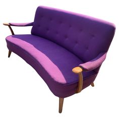 a purple couch sitting on top of a wooden frame