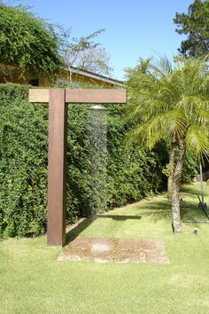 a large wooden cross sitting in the middle of a lush green yard