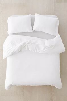 an unmade bed with white sheets and pillows