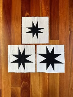 three black and white quilts on wooden floor with one star cut out to look like the other