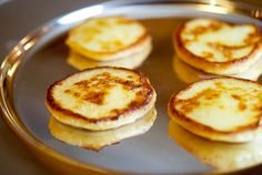 four pancakes on a silver plate with cinnamon sprinkles in the middle,