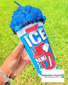 someone holding up a frozen drink with blue sprinkles on it in the grass